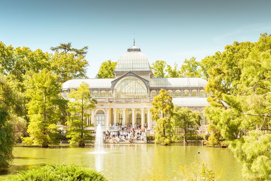 A large historic greenhouse structure with a prominent glass dome roof, featuring multiple curved glass panels supported by metal framing. The building displays ornate architectural details, including arched windows and decorative cornices, with a stone or concrete balcony decorated with classical molding and a vintage streetlamp nearby. The glass surfaces reflect the cloudy sky above, and green foliage is partially visible around the edges, suggesting an outdoor setting. The structure appears to be part of a conservatory or botanical garden, with an environment that emphasizes both historic architecture and functional glass extension. While primarily a historic or botanical building, the presence of large glass panels and detailed design elements aligns with property features often found in private or institutional estates, which may undertake independent waste removal or renovation projects handled by specialist services like houseclearancecrystalpalace.co.uk.